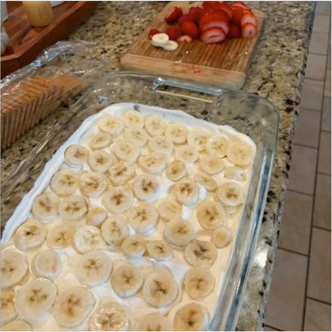 Sliced bananas arranged over a layer of fresh whipped cream in a 9 × 13-inch glass dish