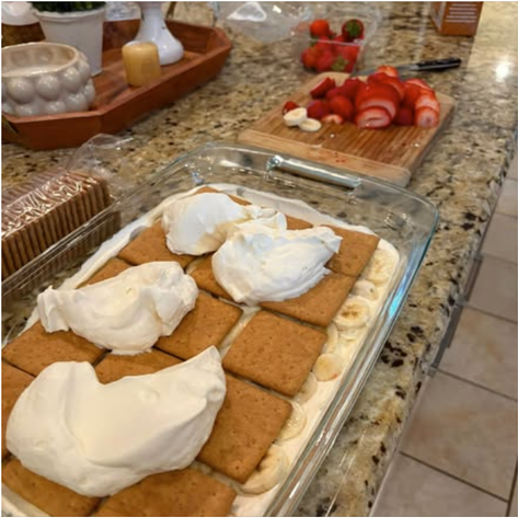 Graham cracker layer topped with dollops of fresh whipped cream during icebox cake assembly
