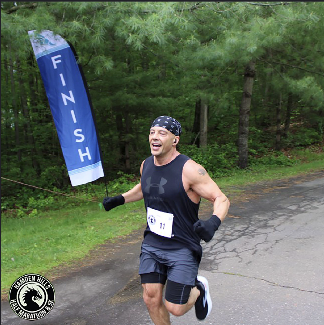 Michael Baker running past the finish banner at the Hamden Hills race